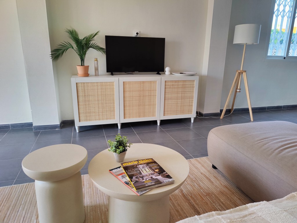 The living garden room, featuring sleek modern furniture set against a backdrop of white walls, black tiled floors, and lu...